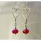 A pair of earrings featuring shaped argentium wire hearts from which red crystal beads dangle. For Valentine's Day, or any day!